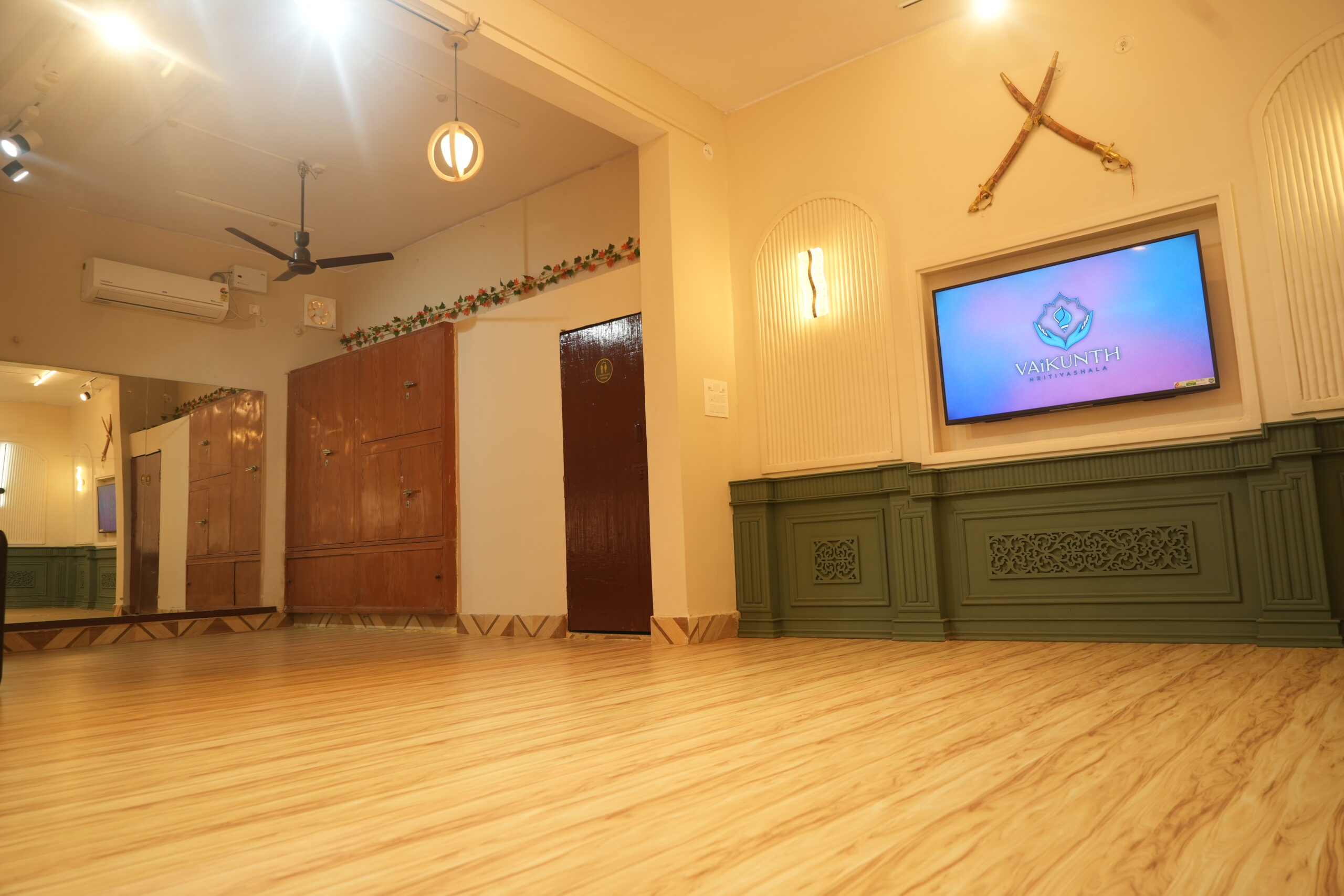 Dance studio with wooden cabinets, mirror, and TV display