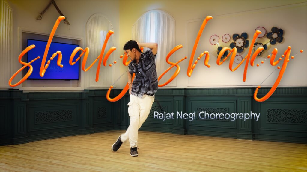 A male dancer performing a dynamic step during a "Shaky Shaky" dance cover at Vaikunth Nrityashala, choreographed by Rajat Negi. The dance studio interior features elegant green paneling and floral wall art.