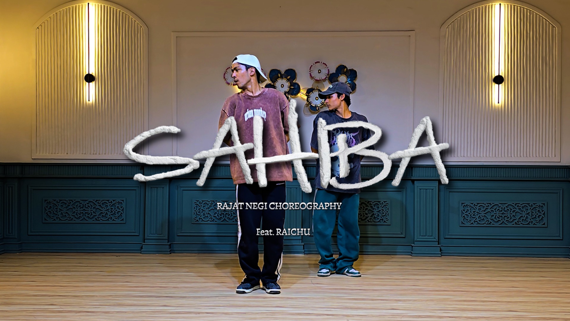 “Two male dancers performing choreography in a studio with elegant wall lights and wooden flooring, with ‘SAHIBAA’ title text overlay and Rajat Negi choreography credit.”